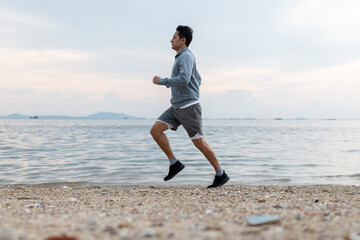 Asian man is running on the beach, exercise cardio workout concept.