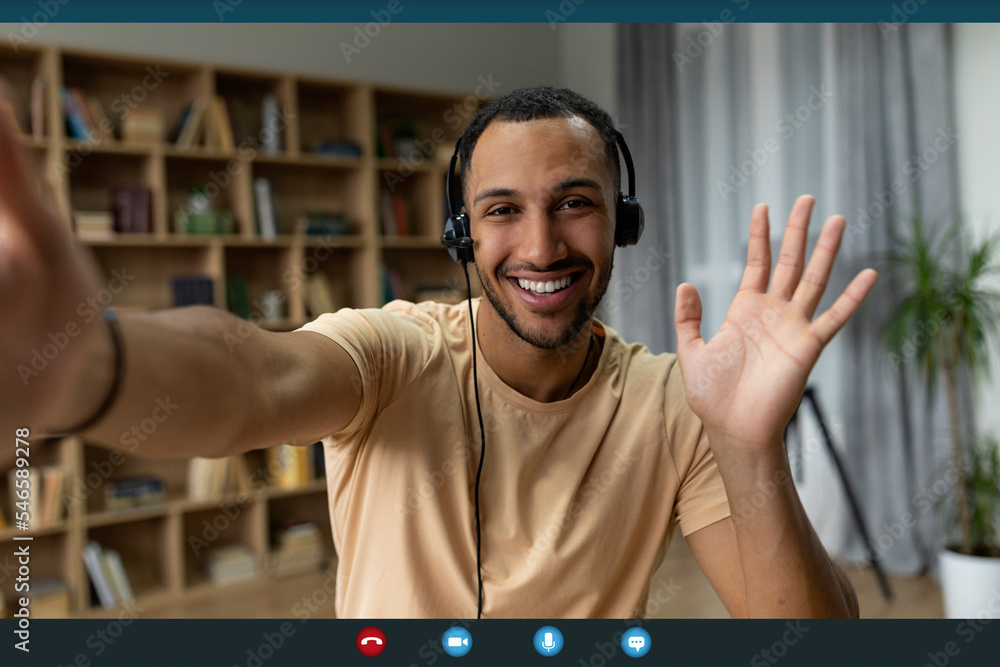Poster web conference. happy arab freelancer man in headset making video call and gesturing hello, monitor 