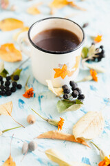 Autumn still life. A cup of tea and yellow autumn leaves on a concrete light background