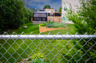 Suburban backyard decks and garden behind a chain-link fence