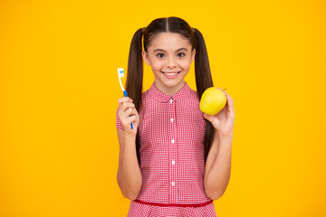 Portrait of caucasian teen girl holds a toothbrush brushing her teeth, morning routine, dental hygiene, isolated on yellow background. Happy teenager, positive and smiling emotions of teen girl.