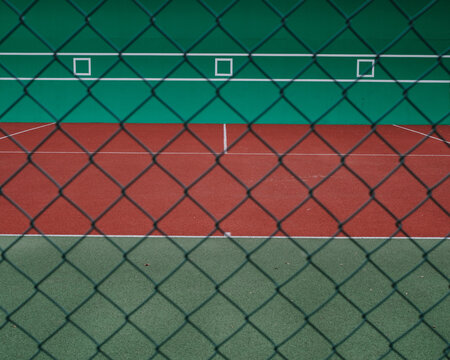 Geometryczne kształty kortu tenisowego widziane zza siatki