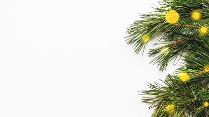 Festive banner with pine tree branches and light bulbs bokeh. White background with copy space and decorations for Christmas and New Year celebration.