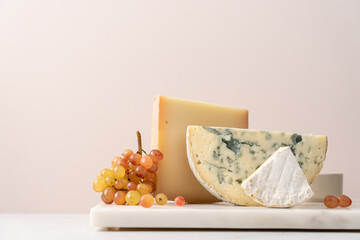 Camembert, blue cheese, hard cheese and grapes on marble board and light background. Set of cheeses...