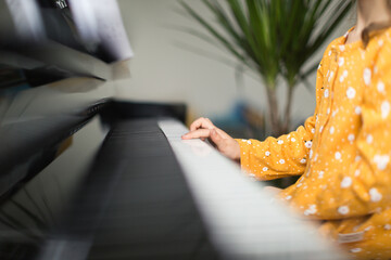 Little blond girl practicing music with the piano