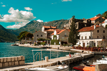 sunny day at montenegro perast sea side, restaurants, boats, stone historical buildings with red...