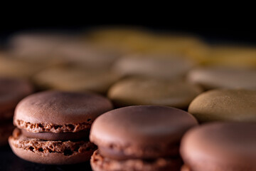 chocolate, coffee, vanilla, lemon and strawberry macaroons on black background