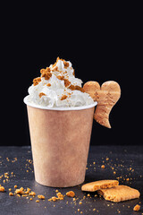Paper cup with hot drink with whipped cream on dark background. Recycling and eco friendly concept.