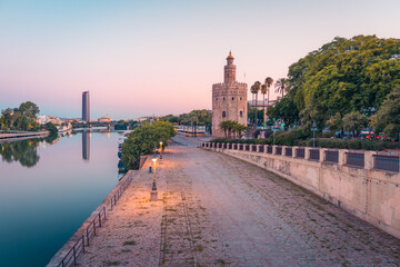 Historical tower of Seville near river against modern skyscraper