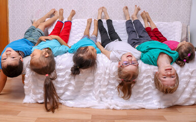 kids are lying on their backs on sofa, looking at camera