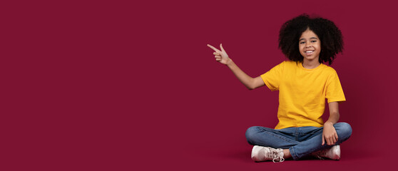 Happy african american kid girl pointing at copy space