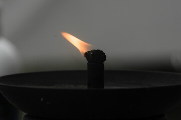 Closeup of a flame on a thread-wick candle in a dark room