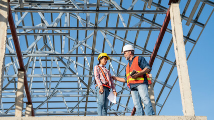 female worker inspects work with a middle-aged male engineer to discuss the problem of the construction of a steel frame for the house's roof in a project under construction.