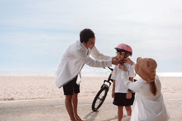 Family on the beach they are enjoy bicycle. Happy father, mother and son, daughter enjoying road trip the summer holidays.Parents and children are riding on a bicycle with a sea travel trip exercise