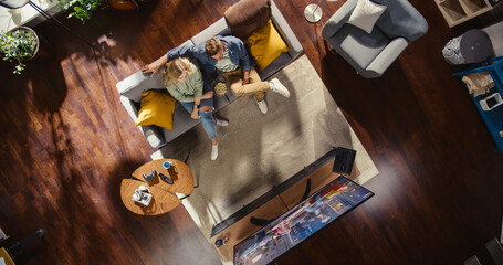 Top View Apartment: Lovely Couple Watching Television in the Stylish Living Room. Looking at the TV...