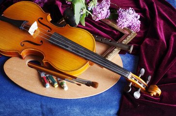 Painting, music, literature. Artist palette, brushes, violin, pipe, notepad, fountain pen, inkwell on a blue tablecloth..