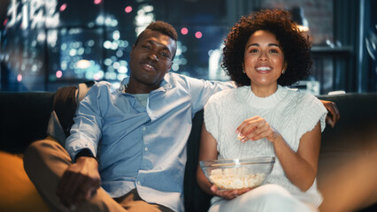 Family Home Movie Theatre. Black Loving Couple Enjoy Watching Comedy Movie and Eating Popcorn During the Evening. Boyfriend and Girlfriend Laughing and Talking About Favourite Comedian. - obrazy, fototapety, plakaty