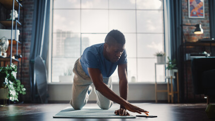 Athletic Black Man Doing Push Up Exercises and Using Mobile Smartphone as Timer. Authentic Male...