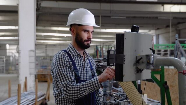 Operator of machine. Industrial worker wearing safety uniform and helmet indoors in factory