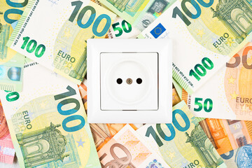 White socket over many Euro banknotes as background. Concept of increasing prices for electricity in Europe. High energy cost, world and Europe's energy crisis concept