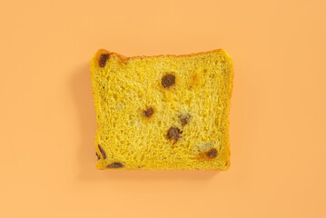 A slice of vegan pumpkin with raisin bread on orange background