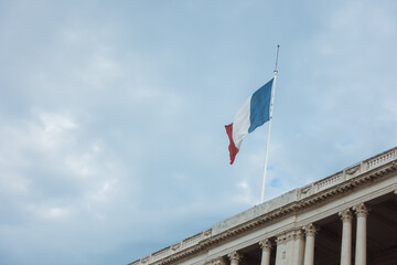France flag waving in the wind on top of administrative building against the dark rainy sky. France travel concept. High quality image