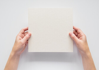 female hands hold empty square cardboard banner on white background. empty space for text