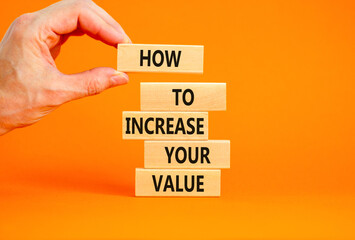 Increase your value symbol. Concept words How to increase your value on wooden blocks. Businessman hand. Beautiful orange background. Business how to increase your value concept. Copy space.