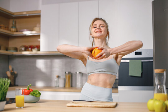 Fit woman on a kitchen cut a fresh healthy oranges with a knife