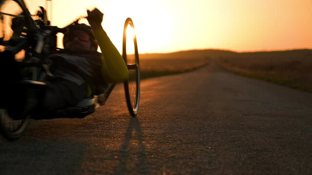 Scenic Shot of a Young Man Athlete with disability Riding a Handcycle. Adaptive Exercise Outdoors at Sunset . High quality 4k footage