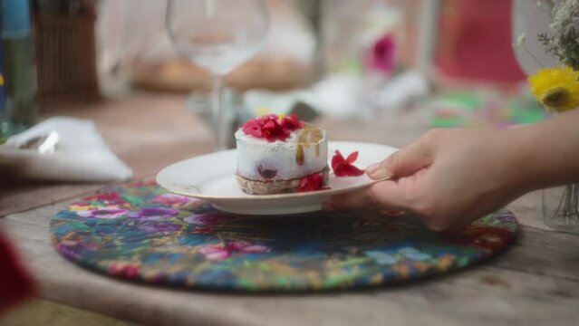 Gourmet dessert with red flowers served on a colorful placemat. Slow motion, shallow depth of field.
