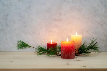 Three candles lit for the third Advent, pine branch as a simple, minimal decoration on a light...
