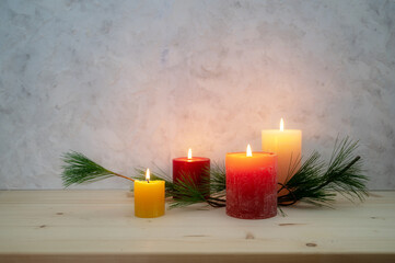 Four candles lit for the fourth Advent, pine branch as a simple, minimal decoration on a light...