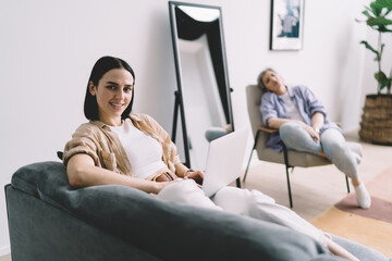 Young female student using laptop while sitting at home with mother