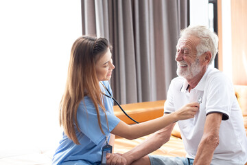 Fototapeta premium Caring nurse with senior man sitting in the bedroom . caucasian man. Discussing. Caring caregiver and senior citizen. Nurse helping senior patient . Young nurse helping elderly man