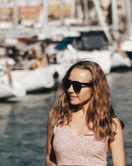 Portret radosnej kobiety w okularach przeciwsłonecznych w porcie jachtowym, Larnaka, Cypr