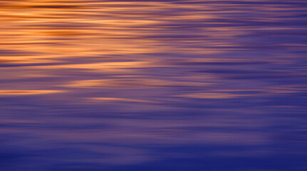 Colorful motion blur background of morning sunlight reflection on ripples and blue sea surface
