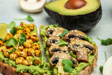 Healthy avocado toasts with chickpeas and mushrooms on a light background, vegetarian vegan food. top view. place for text