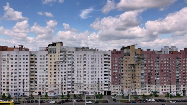 Movement along a long multi-storey building with windows, balconies and loggias. Blue sky with fluffy clouds