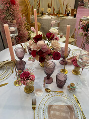 Festive table setting in pink purple red style with candles and flowers.