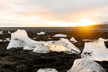 Ice chunks at black beach in sunset