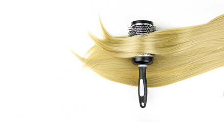 Fototapeta premium Round brush combs with long blond hair closeup. Round hair brush with highlight hair in it.