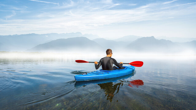 Man in a kayak on a lake in front of big mountains