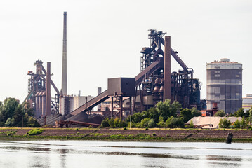 Blasting furnaces, smokestack and gasometers in a riverside integrated steel plant - obrazy, fototapety, plakaty