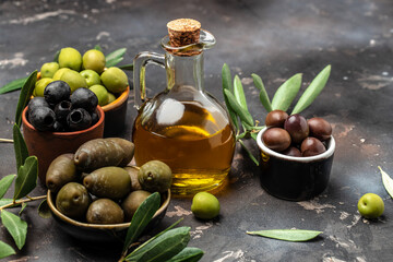 Mixed types of olive in the bowls and olive oil on a dark background, banner, menu, recipe place for text, top view