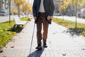 Blind man close-up with a walking stick. Walking down the street