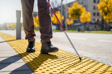 Close-up of a blind man with a walking stick. Walks on tactile tiles for self-orientation while...