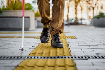 Close-up of a blind man with a walking stick. Walks on tactile tiles for self-orientation while...