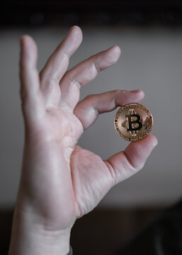 Hand holding and showing a golden Bitcoin