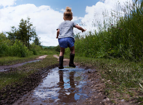 Rear view of girl jumping in puddle